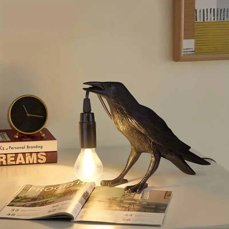 Crow holding light bulb illuminating an open book on a desk