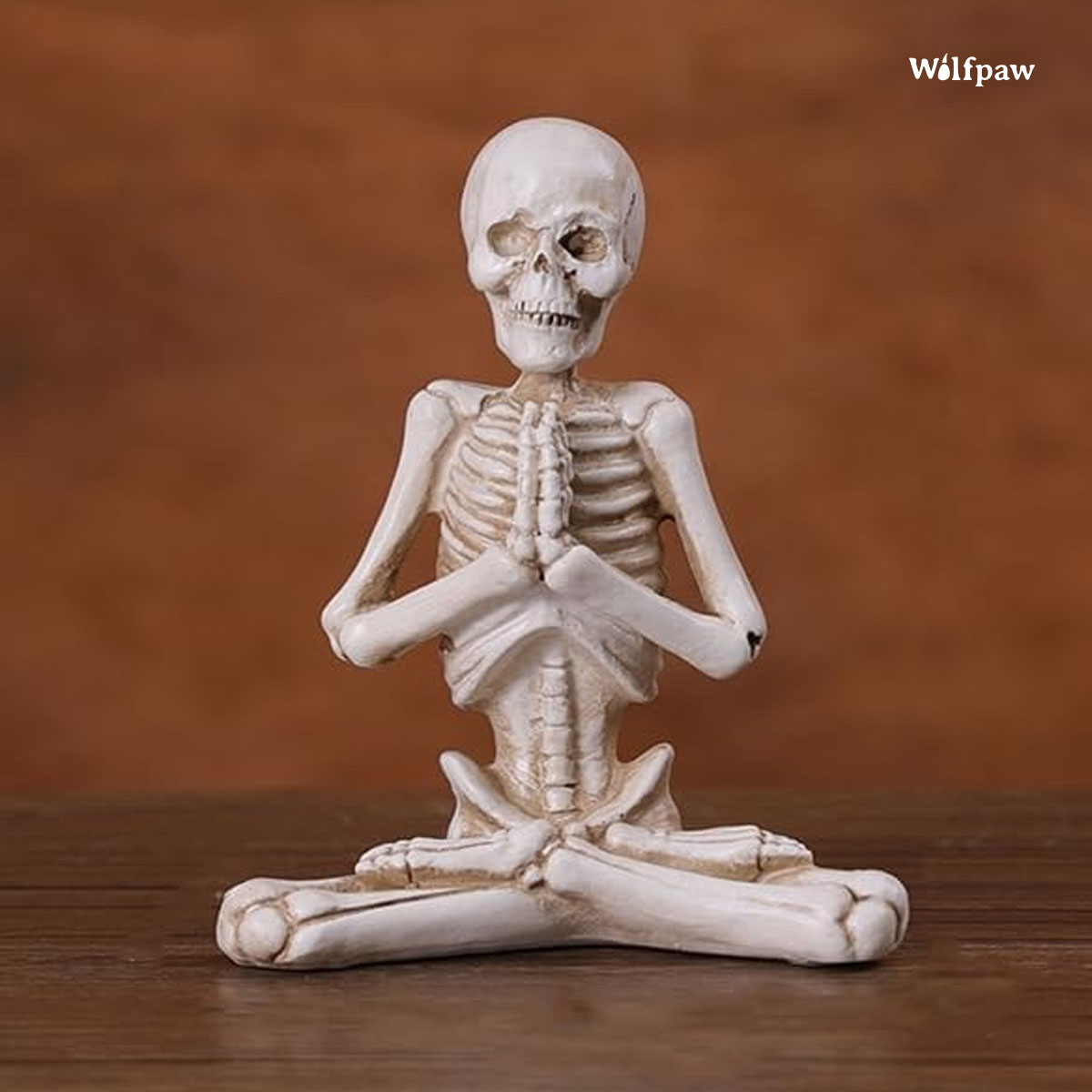 A skeleton in a yoga pose sits serenely on a wooden table, embodying tranquility and mindfulness in a unique setting.